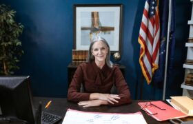 Professional woman in office with flags, showcasing leadership and confidence.