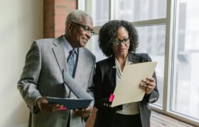 Two business professionals reviewing documents in a corporate office setting.