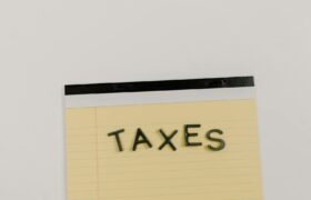 A flat lay of the word 'TAXES' on a yellow notepad, ideal for financial content.
