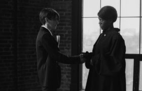 Black and white image of two women shaking hands in a courtroom setting, signifying agreement.