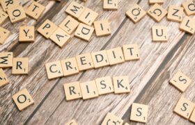 Scattered wooden letter tiles spelling 'credit risk' on a rustic wooden surface.