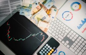 Overhead view of financial tools with Euro banknotes on a desk showing market trends and graphs.