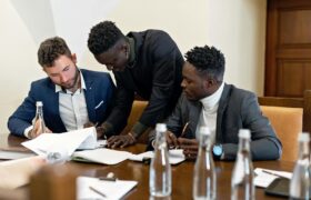 Three professionals working together at a table, discussing documents in an office setting.
